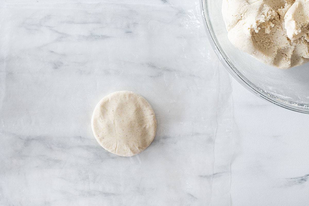Masa para tortillas un poco aplanada entre dos trozos de plástico.