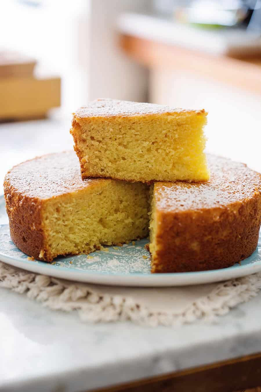 El pastel de limón y queso ricotta en un plato y con una rebanada encima.