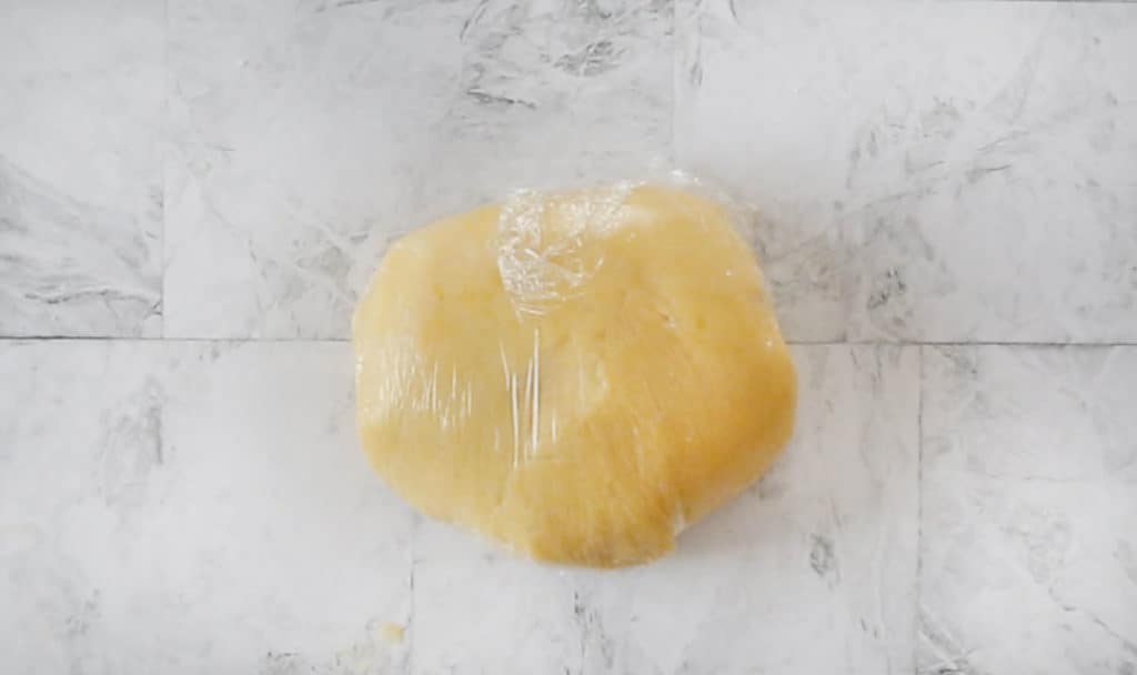 Masa lista en una bola cubierta con plástico para poner a reposar en el frigorífico.