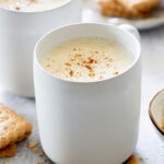 Atole de Avena, aka oatmeal atole served on white cups with powdered cinnamon sprinkled on top.