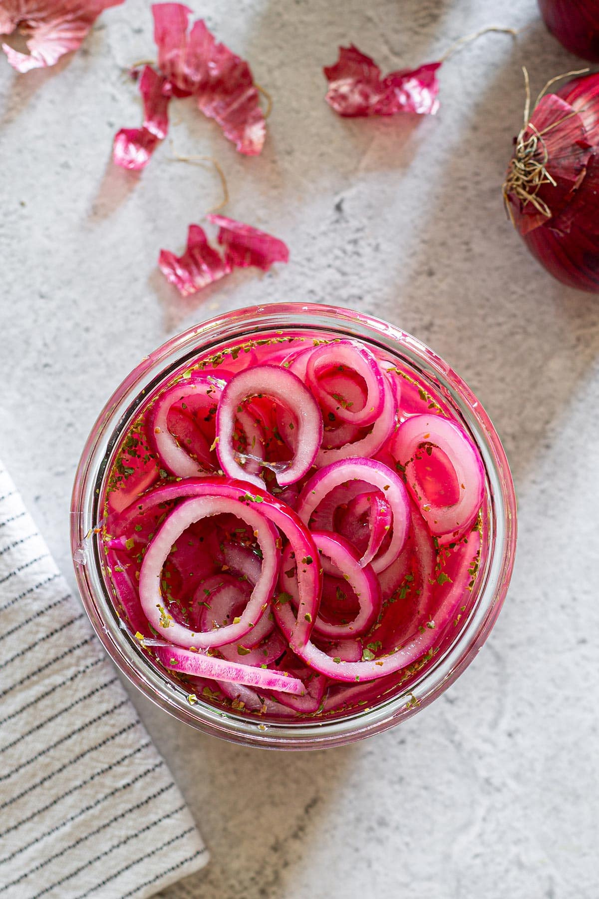Mexican pickled red onions in a jar on a concrete surface.