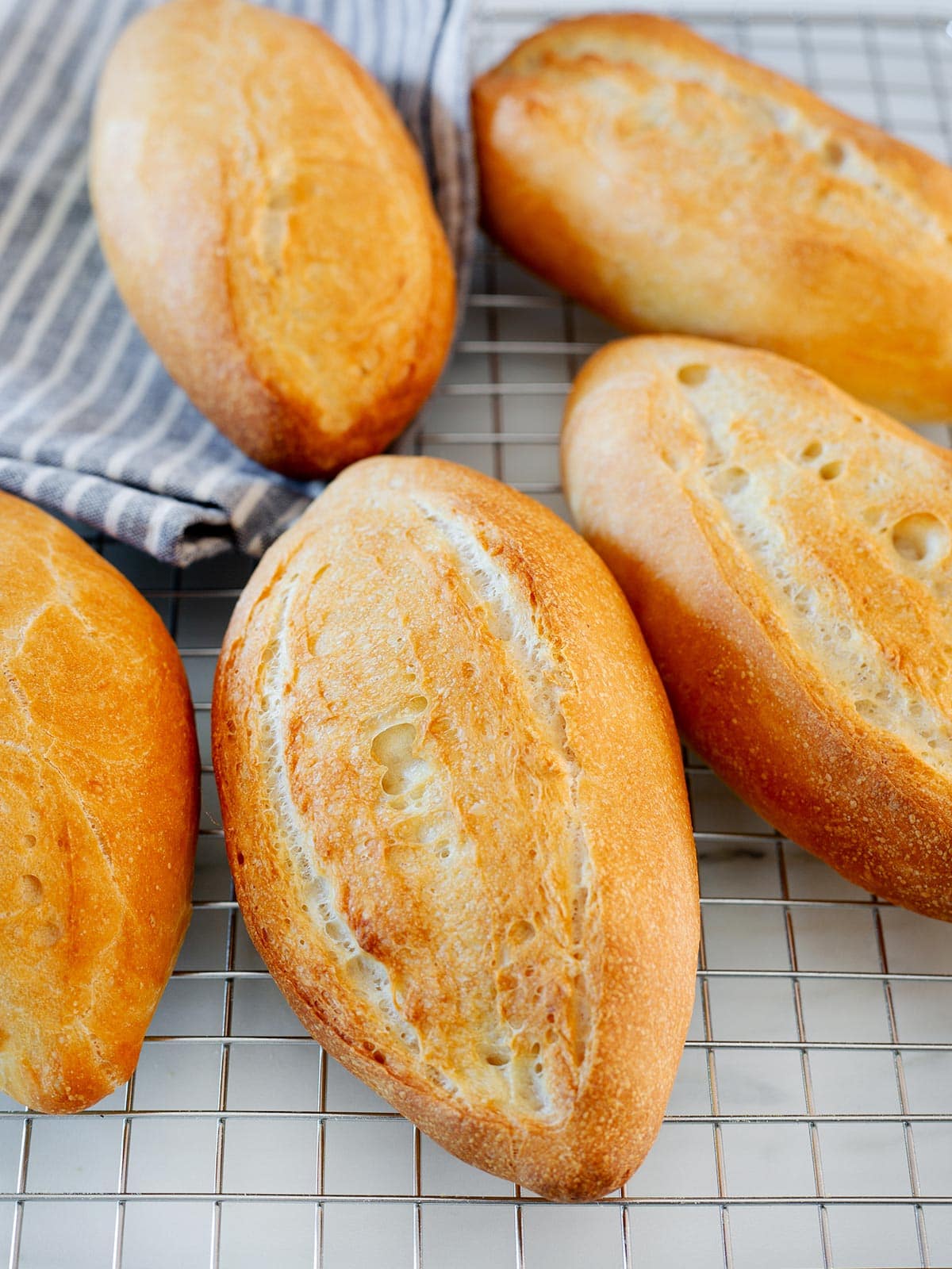 Bolillo bread rolls on a cooling rack.
