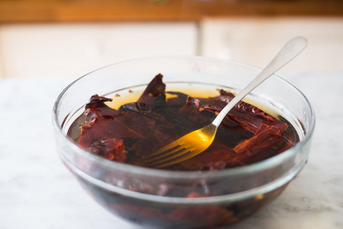 Mexican chilies soaking in a bowl with hot water.