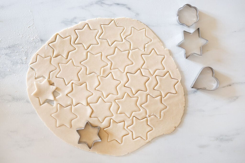 The hojarascas dough cut into stars with other cookie cutter shapes on the side.