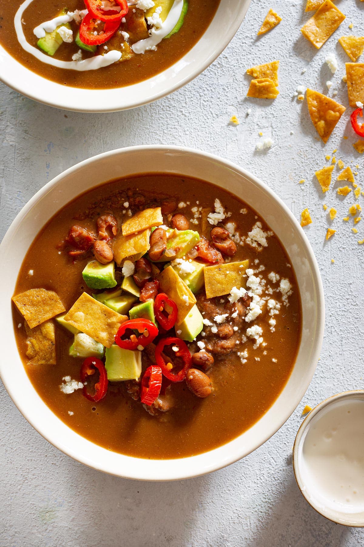 Sopa de Frijoles. Mexican pinto bean soup, served with tortilla chips, avocado, and cheese.