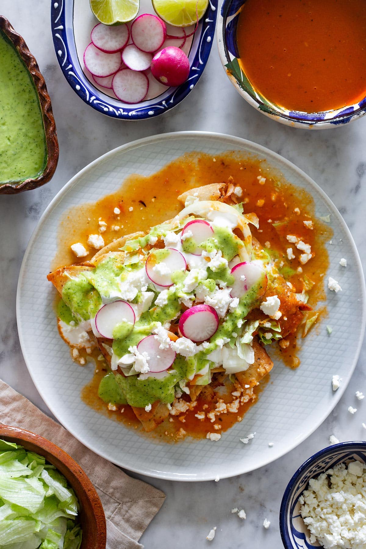Crujientes flautas de pollo Mexicanas con lechuga, crema, queso, salsa guacamole y rabanitos.