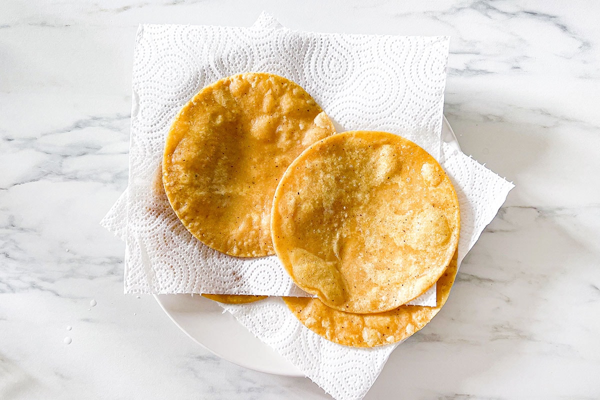 Lightly fried tortillas in a plate with kitchen paper towels.