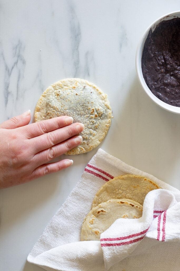 Lightly flatting a panucho filled with beans.
