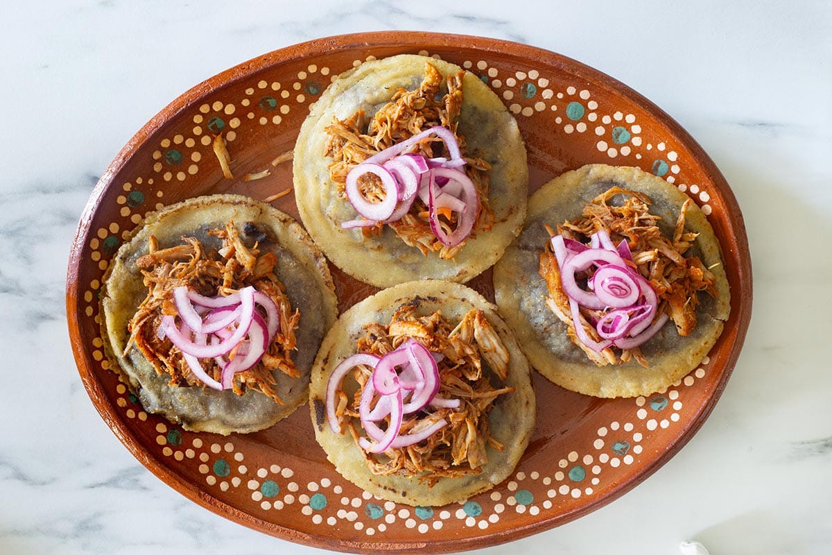 Some panuchos yucatecos half assembled on a platter.