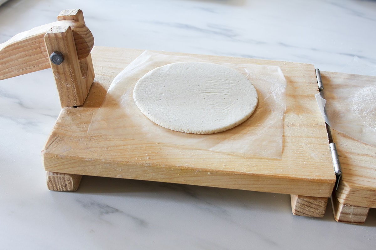 A panucho shell made of masa dough on a tortilla press.