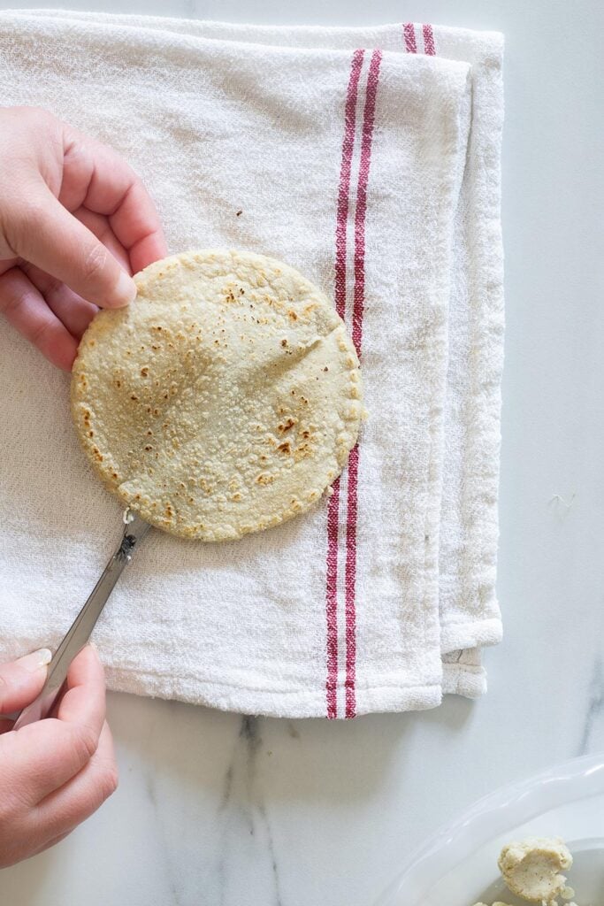 Cutting a tortilla with a table knife to make a pocket for the panucho filling.