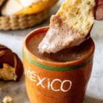 Dipping sweet bread concha into the hot chocolate.