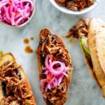 Tortas de cochinita assembled on a marble surface with some garnishes on the side.