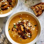 Two bowls with crema de champiñones and some crusty bread on the side.
