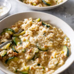Risotto con zucchine e salsiccia (zucchini risotto and sausage) served in plates.