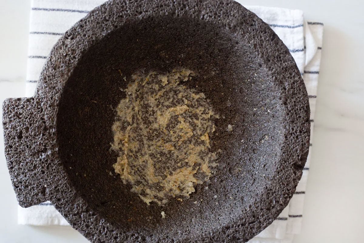 Paste of smashed peppercorns, sea salt, and garlic cloves in a molcajete.