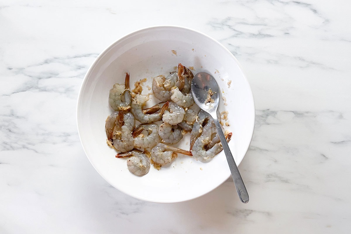 Fully coated shrimp with garlic paste in a bowl.