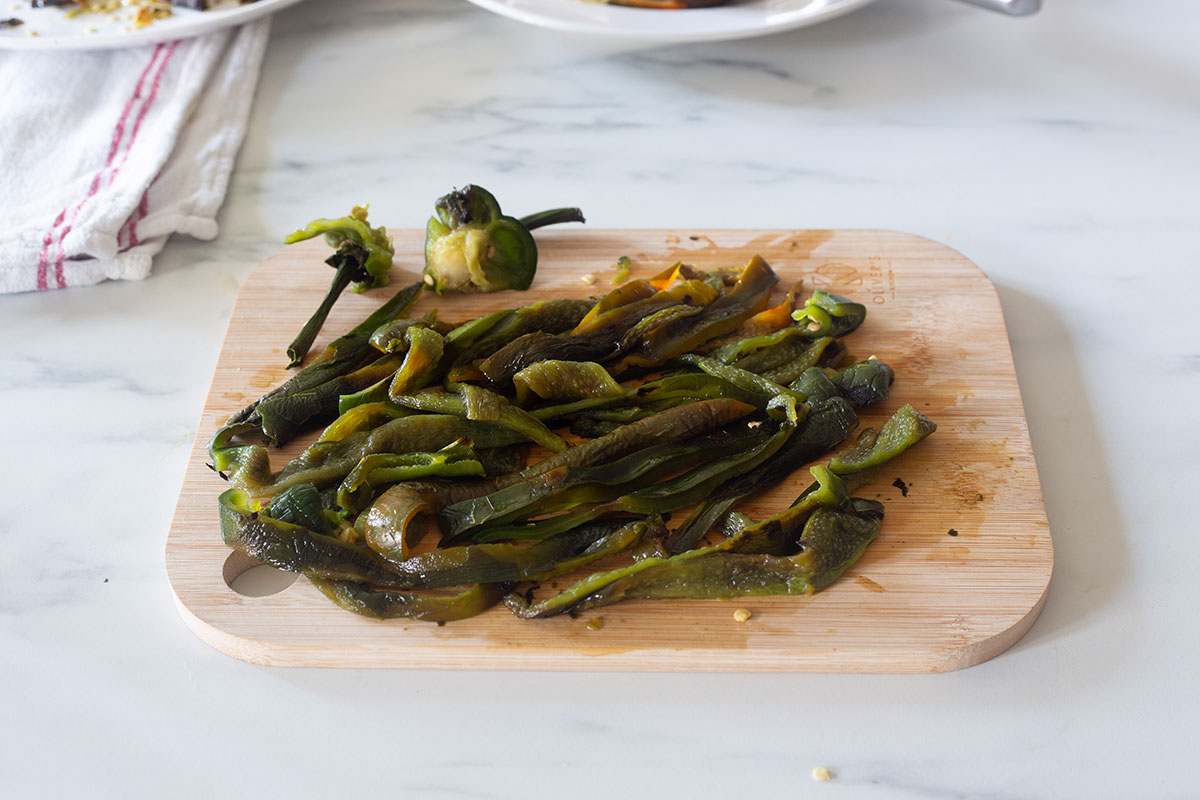 Strips of roasted poblano peppers on a cutting board.
