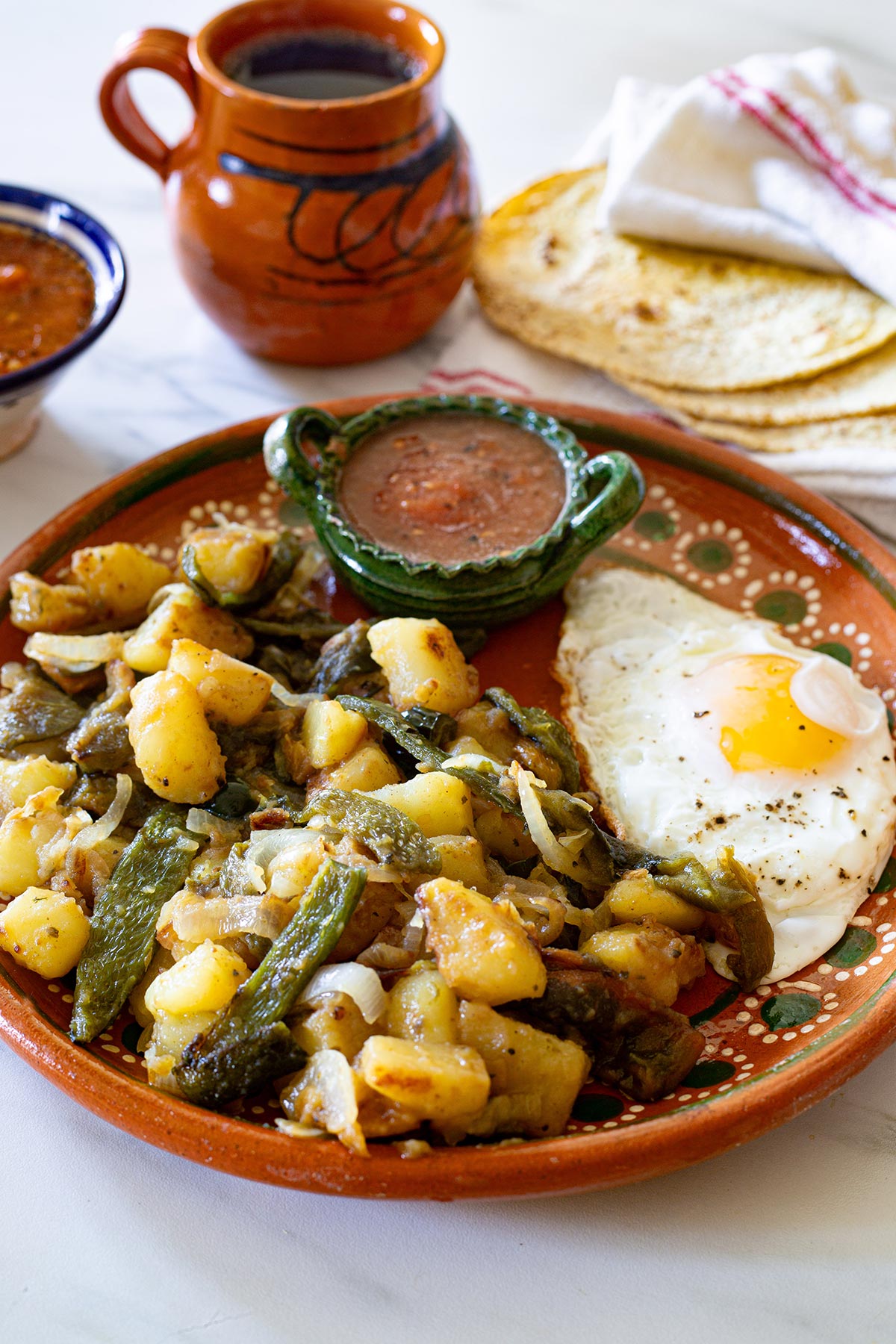 Papas con Rajas poblanas in a plate with a fried egg on the side.